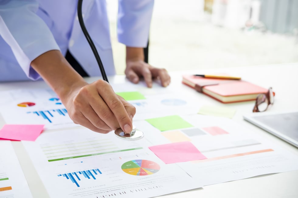 Doctor Holding Stethoscope to Graph and Analysis Data